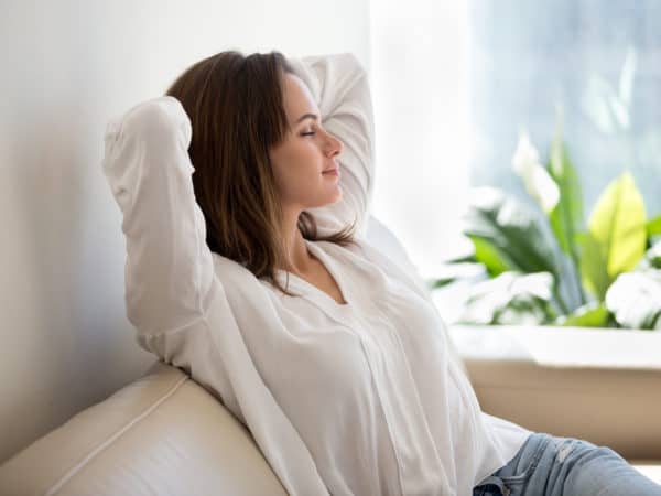 Relaxed woman resting breathing fresh air at home on sofa