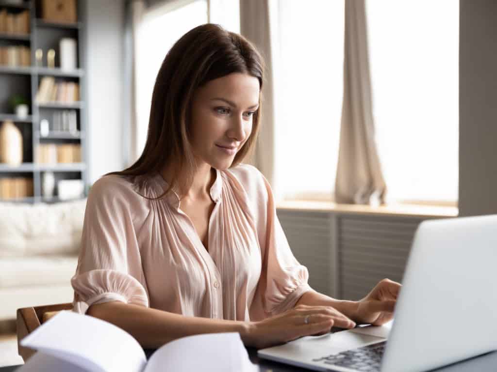 Pleasant happy young woman freelancer working on computer.