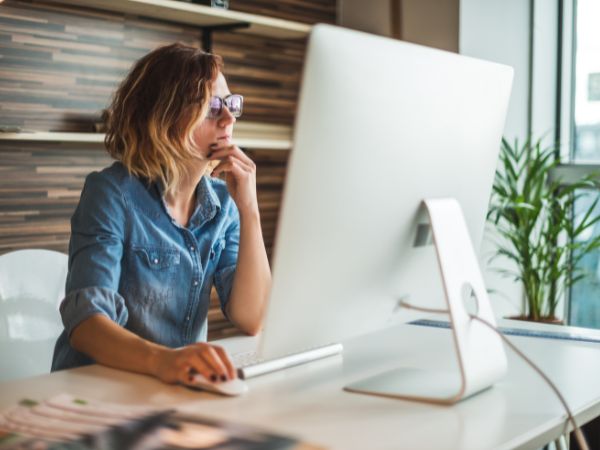 Photo of someone sitting at their desk looking at repurposing content for their business. 