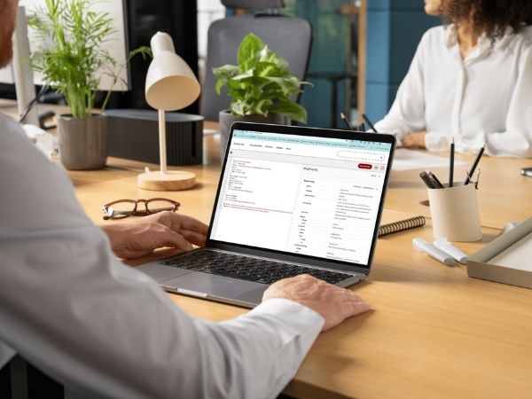 A professional reviewing structured data validation with Schema.Org Validator on a laptop in a modern office environment with plants and documents on the desk.