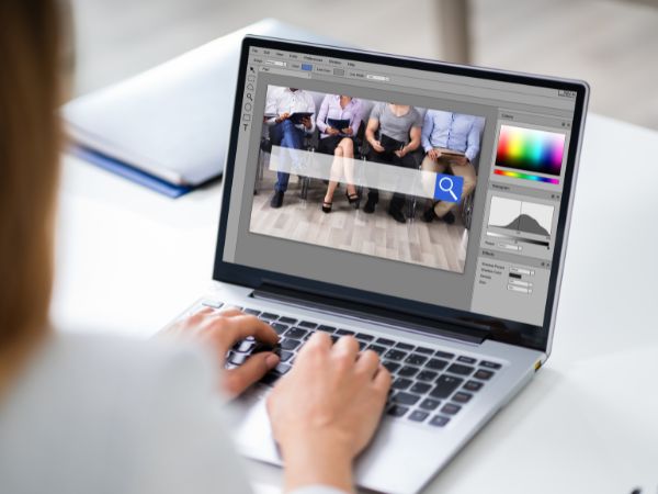 A person editing photos on a laptop, representing the creative process of photo editing.