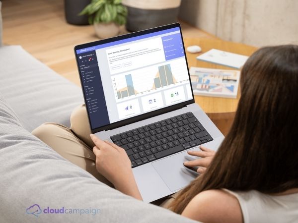 Person using a laptop with Cloud Campaign’s social media analytics dashboard displayed. Branded Cloud Campaign logo in bottom corner.