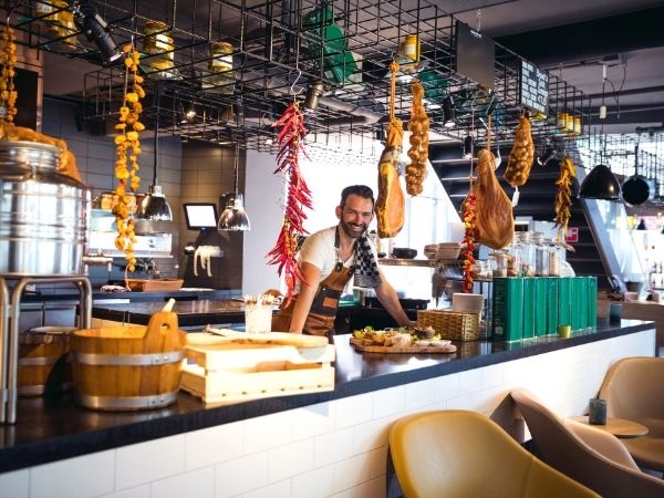 Local café owner behind a vibrant counter, representing the small businesses that stand to gain first from Instagram posts now appearing on Google Search.