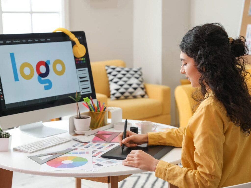 Emily - Freelance graphic designer working on logo design at her home office desk, engaging in creative work for clients in a bright and professional setting